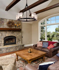 Living room with 5 Light Black Farmhouse Chandelier for Dining Room and Foyer hanging from wood beams, rustic decor, stone fireplace.