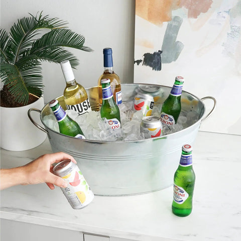 Large Galvanized Ice Tub For Parties With Sturdy Handles Six Point Three Gallon Beverage Cooler For Beer Wine Soda And Bottled Water Rustic Indoor Outdoor Drink Bucket displayed on a counter with drinks inside.