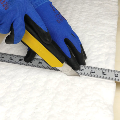 Ceramic fiber insulation blanket, white, 2 in thick, being cut with a yellow utility knife.