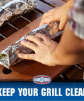 Hands wrapping food in Extra Wide Aluminum Foil Roll For Grilling And Baking Heavy Duty 18 Inch By 100 Sq Ft on a wooden surface.