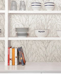 Kitchen with Treetops Peel And Stick Wallpaper In White And Off White visible behind white shelves with dishes and books