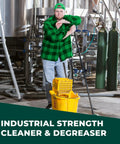 Person in industrial setting with mop, using Heavy Duty Grime Busting Cleaner And Degreaser Concentrate, Non Toxic And Biodegradable, 5 Gallons.
