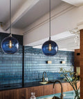 Hand Blown Glass Pendant Light For Kitchen Island Capri Blue Globe Seeded Bubbles Lit Eight Point Seven Inch Diameter 60 Inch Adjustable Cord ETL Listed Modern Ceiling Light over kitchen island