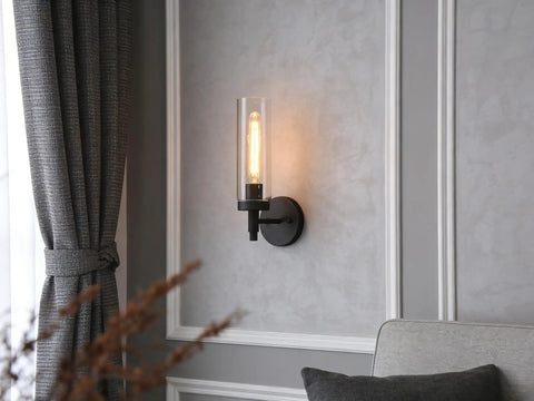 Matte Black Rustic Industrial Wall Sconce Light With Tubular Clear Glass Lampshade on gray wall in living room