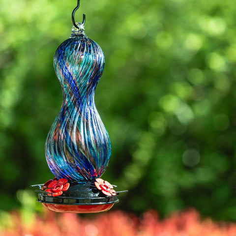 Outdoor Hand Blown Glass Hummingbird Feeder With 24 Oz Capacity And Four Feeding Ports in a garden setting