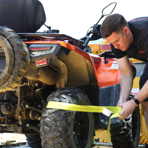 Man using Heavy Duty Car Tie Down Straps With Flat Hooks 10000 Lb Break Strength 4 Pack Tire Ratchet Straps For Trailers Trucks And UTVs 10Ft Lasso Straps Fit All Size Tires Smooth D Ring Hooks For Easy Mounts On Side Rails on ATV tire.