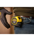 Man holding Tape Measure With Blade Armor Built Tough 8 M Metric, Shock Resistant, Mylar Coating on belt loop