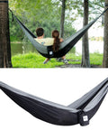 Parachute Nylon Hammock Single With 2 Tree Straps set between trees near a lake, showing lightweight camp gear for outdoor use.