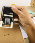 Built Tough Self Inking Date Stamp For Shipping And Expiration Tags Black Ink With Spin Bands being used on a cardboard box.