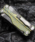 Folded Ultra Lightweight Titanium Alloy Multitool Pliers With Camouflage Finish on rock background