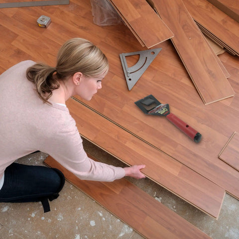 Person using Floor Lifter Pro Demolition Tool for easy removal of hardwood floors, showing tool placement and floor pieces.