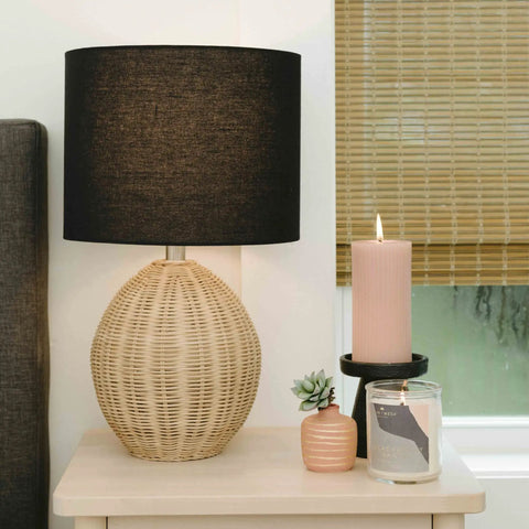 Boho Woven Rattan Table Lamp With Black Linen Shade In Natural Finish, Rotary Switch, on bedside table with candle and plant