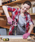 Woman using Pink Cordless Drill Set For Women with 12 Volt Power and 2 Ah Battery in a workshop setting, wearing gloves.