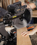 DOVAMAN 12-Inch dual-bevel miter saw; front-side view cutting wood with spinning blade and clear guard, corded