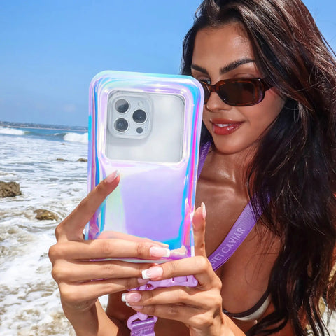 Person holding Waterproof Phone Pouch With Lanyard IP68 Floating Case For All Phones in Lavender Holo, using phone at the beach