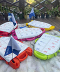 Spearfishing Float Buoy With Foldable Carbon Fiber Flagpole and D Ring Handles in orange, red, yellow, green on a deck
