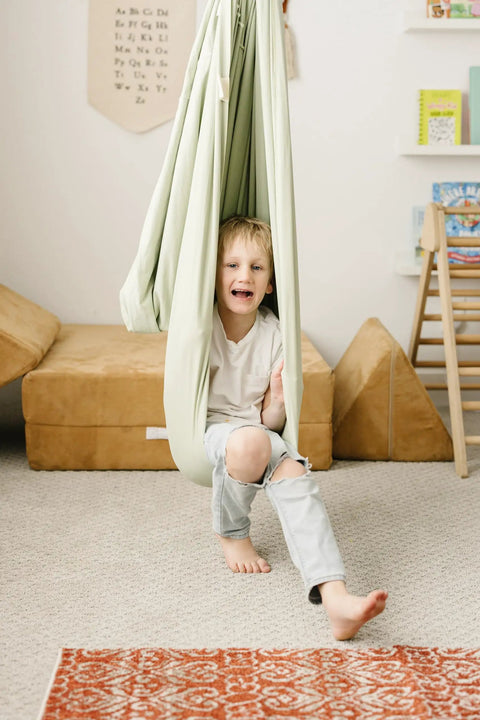 Child in Ultimate Chill Cotton Sensory Cocoon Swing For Kids Autism And Adhd Therapy Support Indoor Outdoor Hammock Desert Sage.