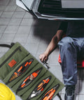 Mechanic using Sturdy Canvas 16oz Tool Roll Up Bag For Wrenches And Tools with five zipper pockets in a garage setting.