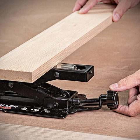 Adjustable Miter Saw Roller Stand With 140 Lb Capacity Height From 2 In To 6.3 In Ball Bearing Rollers For Smooth Free Rolling And Easy Material Loading Hands Free Operation Heavy Duty Support in use, showing wood plank being adjusted with focus on knobs and rollers.