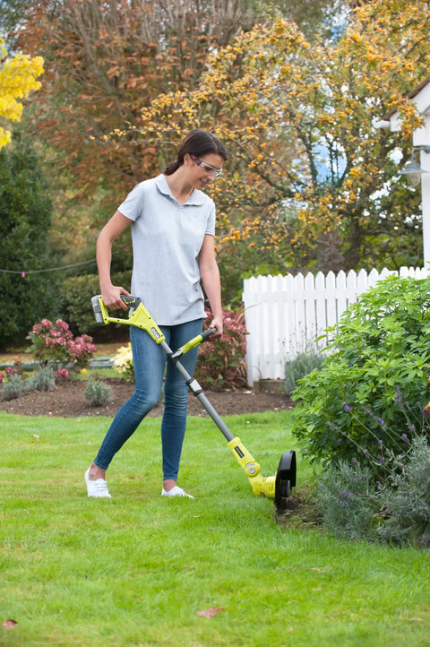 Woman using Pro Grade 18 Volt Cordless Grass Trimmer With Dual 2.0 Ah Batteries And Telescopic Handle on grass.