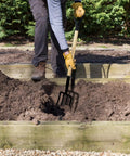 Person using Heavy Duty 45 Inch Garden Fork 4 Tine Pitchfork with Forged Steel Y Grip in garden bed