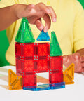 Child building with Travel Magnetic Construction Set With 26 MicroMAGS Tiles, colorful blocks on table, green background