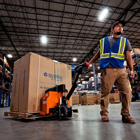 Premium Global Industrial Self-Propelled Electric Pallet Jack Truck Featuring Dual 60Ah Batteries in a warehouse handling a box.