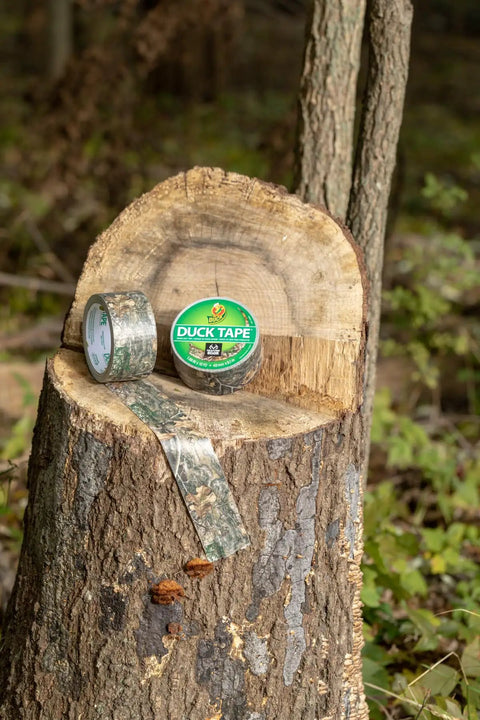 Realtree Camo Duct Tape Roll 1.88 Inch Wide By 10 Yards Beefy Heavy Duty Craft Tape on tree stump in forest setting.