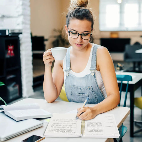 Woman using Daily Planner With Hourly Schedule Spiral Notepad For Easy Tasking And Appointment Organization at desk with coffee