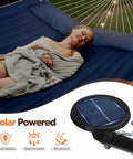 Double Outdoor Hammock With Twelve Foot Stand And Solar Powered Lights Portable Two Person Hammock With Stand In Dark Blue For Backyard Patio Camping And Relaxation showing a person lying peacefully with integrated solar lights.