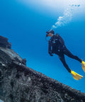 Diver wearing Glide Front Adjustable Scuba BCD With Balanced Power Inflator for recreational diving near underwater ruins