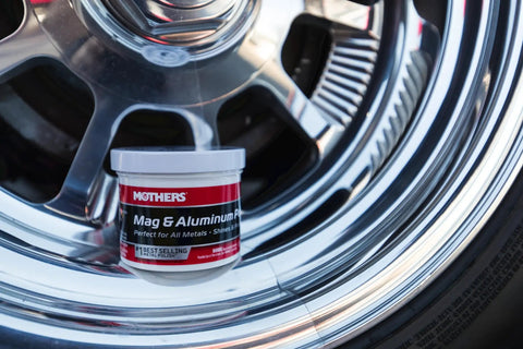 Mag And Aluminum Metal Polish That Restores Dull Surfaces To A Showroom Shine Easy Buff Perfect For Aluminum Stainless Steel Brass Chrome And More 5 Oz Jar next to shiny chrome wheel.