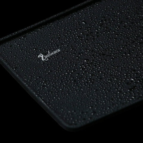 Close-up of black Espresso Tamper Mat Non Slip Food Grade Silicone Pad For Tamping Station Barista Accessory with water droplets