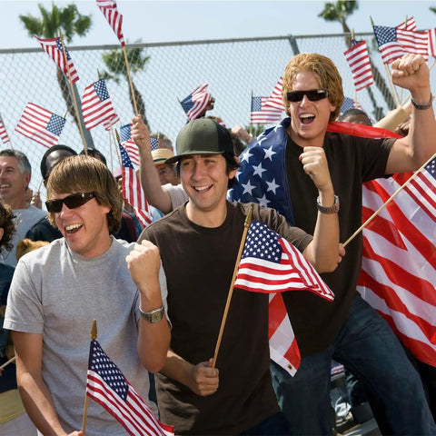 Men holding 12 Pack 8x12 Inch All American Flags on sticks with wood poles at a parade for Memorial Day or Fourth of July celebration.