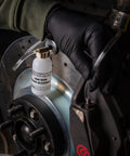 One-Man brake bleeder bottle with clear hose attached to car brake caliper near rotor