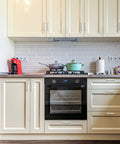 White kitchen with cream cabinets, modern appliances, granite countertop, and backsplash