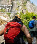 Hikers on a trail with Bear Bell With Magnetic Silencer For Hiking Safety And Wildlife Awareness attached to a red backpack.