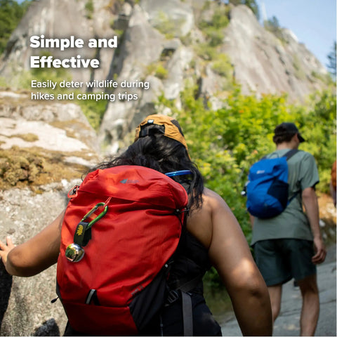Hikers on a trail with Bear Bell With Magnetic Silencer For Hiking Safety And Wildlife Awareness attached to a red backpack.