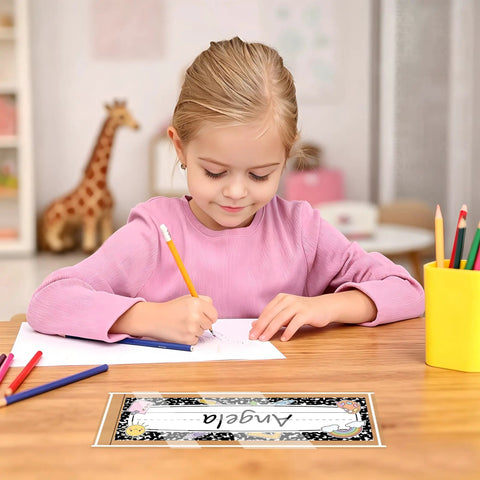 Child writing at desk with 40 Pack Clear Self Adhesive Nameplate Pockets For Desks 10.5 By 3.5 Inches; giraffe toy in background.