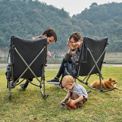 Oversized Folding Rocking Camping Chair With Padded Comfort Portable Rocker For Patio Lawn And Outdoors Heavy Duty Armchair Supports Up To 400 Lbs Gray For Adults being used outdoors by a family with a toddler and dog.