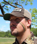 Hunter wearing 3 Color Camo Face Paint Stick For Hunting With Mess Free Application Long Lasting Concealment Makeup in nature