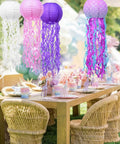 Jellyfish Paper Lanterns 6 Pack Hanging Lit Colorful Lanterns For Mermaid Unicorn Theme Classroom Decor Under The Sea Ocean Birthday Party Decorations For Undersea Parties Classroom Decor And Birthday Celebrations with pink, white, and purple lanterns over a table.