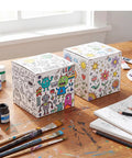 Pack Of 40 5x5x5 White Corrugated Shipping Boxes For Mailing And Packaging decorated with colorful designs on a wooden table