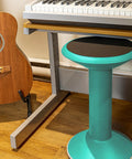 Teal wiggle stool for class and home study by a keyboard and guitar, flexible seating adjustable 12 to 18 inch height