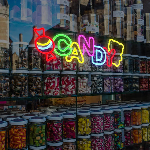 Colorful neon candy sign above jars of sweets in a shop window display