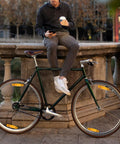Man sitting on stone railing holding coffee next to bike with 4 Pack Bicycle Wheel Spoke Reflectors For Front And Rear Mountain Bike Safety
