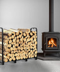 4Ft Firewood Rack Stand Built Tough Heavy Duty Wood Storage Stack Holder next to indoor stove, loaded with firewood logs.