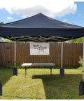 Beefed Up Heavy Duty Canopy Weight Bags Set Of 4 For Instant Outdoor Shelters up to 45 lbs each securing pop-up tent on grass.