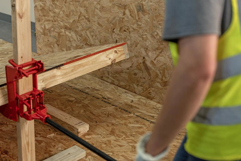 Guardian 2601 portable wall jack installed on a wooden post with a red cast-iron mounting clamp and black pipe