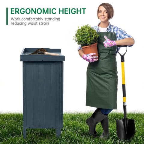 Woman standing beside Outdoor Storage Cabinet With Potting Bench And Metal Tabletop For Garden And Patio, holding plant and shovel
